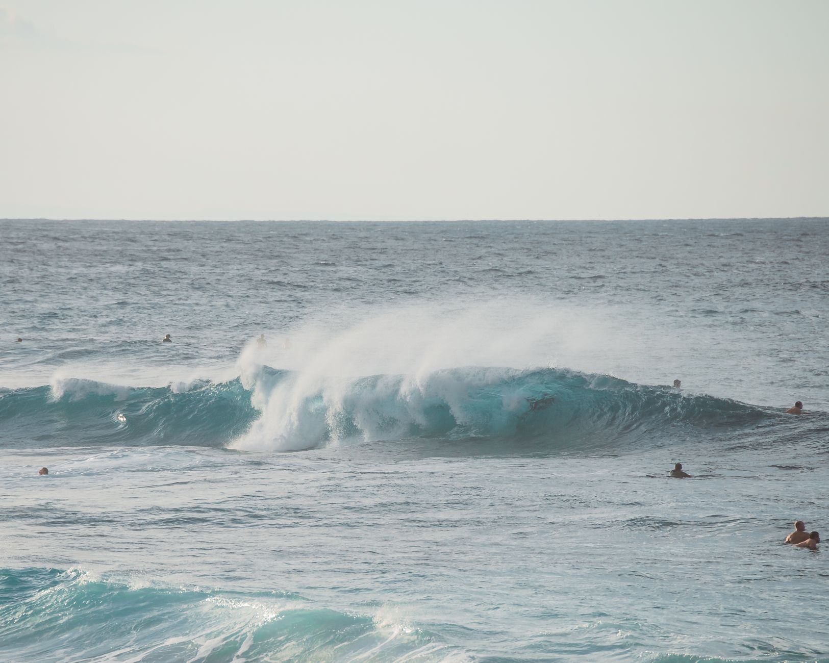 photo of sea wave crashing with people swimming